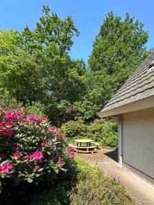 una mesa de picnic en un jardín con flores rosas en Vakantiehuis Bos en Hei Veluwe en Epe