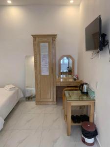 ein Zimmer mit einem Bett und einem Schreibtisch mit Spiegel in der Unterkunft ThiênBảo Hotel in Da Lat