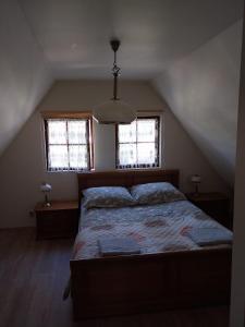 a bedroom with a bed and two windows at Domek na żołędziowej in Morzyczyn