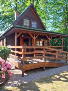 a large wooden cabin with a porch and a fence at Domek na żołędziowej in Morzyczyn