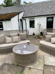 a patio with two couches and a coffee table at Garden Cottage in Gartocharn