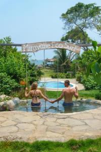 a man and woman in the water holding hands at Miravalle Eco Surf in Sonsonate