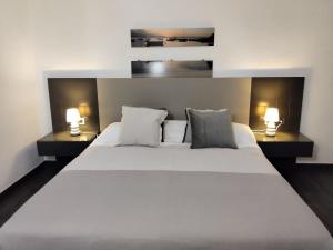 une chambre avec un grand lit blanc avec deux lampes dans l'établissement Apartamento exclusivo, à La Manga del Mar Meno