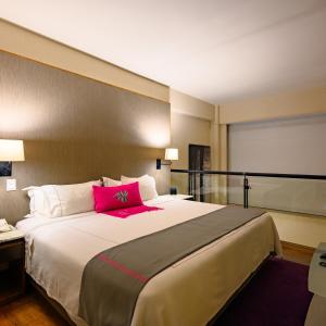 a bedroom with a large bed with a pink pillow at Las Suites Campos Eliseos in Mexico City