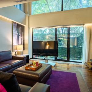 a living room with a couch and a large window at Las Suites Campos Eliseos in Mexico City