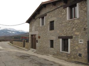 a stone building on a street with mountains in the background at CASA RURAL SANDRA in La Carrera