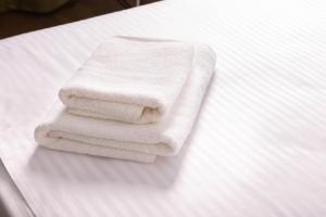 einen Stapel Handtücher auf dem Bett in der Unterkunft Hotel Vila MAX in Durrës
