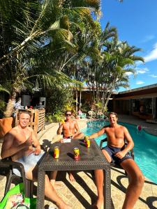 un grupo de hombres sentados en una mesa junto a una piscina en Costa Rica Backpackers en San José