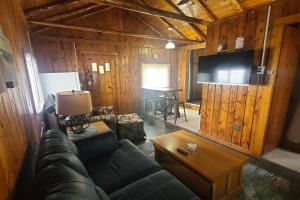 a living room with a couch and a tv in a cabin at Lake Huron - Super Cute Lake Front Cabin (Sleeps 5) in Oscoda