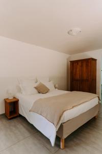 - une chambre avec un lit blanc et une armoire en bois dans l'établissement Habitation TABANON, à Petit-Bourg