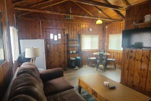 sala de estar con sofá y mesa en Lake Huron - 1 Bedroom, 1 Bath Lake Front Cabin (Sleeps 4) en Oscoda