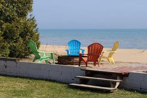 a group of colorful chairs sitting on the beach at Lake Huron - 1 Bedroom, 1 Bath Lake Front Cabin (Sleeps 4) in Oscoda