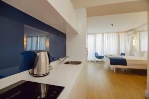 ein Hotelzimmer mit einem Bett und einer Küche mit einem Waschbecken in der Unterkunft Hotel in Orbi City Official in Batumi
