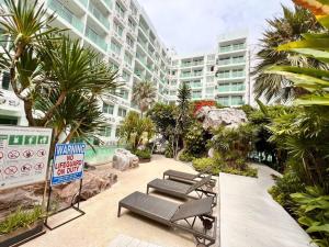 a resort with chairs and palm trees and a building at PALMTREE BREEZE Condo in Amazon Residence in Jomtien Beach