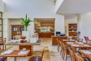 a restaurant with wooden tables and chairs and a kitchen at Fiesta Inn Colima in Colima