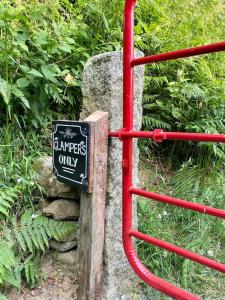 een bord is bevestigd aan een rode metalen poort bij Wicklow Wild Glamping Shepherds Huts at Greenan Maze in Rathdrum
