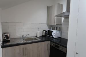 a kitchen with a sink and a microwave at Cosy Studio Perfect For Two in Hanwell