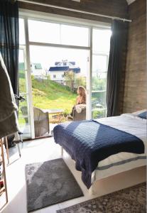 une femme assise sur une chaise dans une pièce avec un lit dans l'établissement Forest house, à Ljungskile