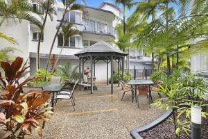 a gazebo with tables and chairs in front of a building at Beachside Mooloolaba in Mooloolaba