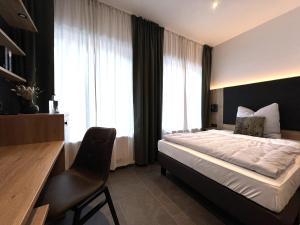 a hotel room with a bed and a desk and window at Haus Kuckenberg in Burscheid