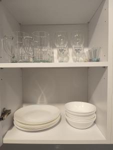 un estante blanco con platos y vasos. en Apartament Siedlce, en Siedlce