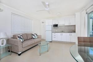 a living room with a couch, coffee table and a tv at Beachside Mooloolaba in Mooloolaba