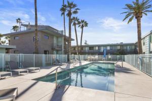 una piscina con sillas, un edificio y palmeras en Walkable OTS, Heated Poolside Mid Century Condo en Scottsdale