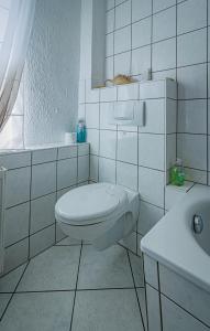een witte badkamer met een toilet en een wastafel bij Wohnen über einem mediterranen Restaurant,Apartment 2 oder 3 in Leipzig