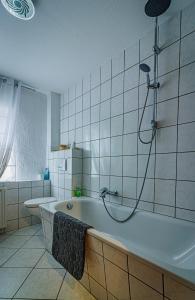 a bathroom with a bath tub with a shower at Wohnen über einem mediterranen Restaurant,Apartment 2 oder 3 in Leipzig