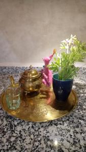 une assiette d'or avec une théière et un bol avec des fleurs dans l'établissement Riad Majdoulina chez JIJI, à Marrakech