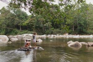 two people are standing on a raft in a river at La Ponderosa Reserve in Buritaca