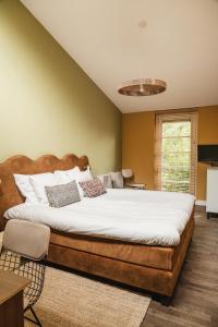 una camera da letto con un grande letto con lenzuola bianche di Zoomers aan het Bos a Castricum