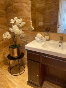 a bathroom with a sink and a vase with flowers at ROYAL Apartment in Kadaň +13 photos