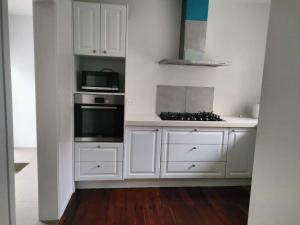 uma cozinha com armários brancos e um forno com placa de fogão em Cozy 5 bedrooms house 7 Rangiatea Road, Epsom em Auckland