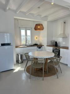 White Villa Milos في آداماس: مطبخ مع طاولة وكراسي وثلاجة