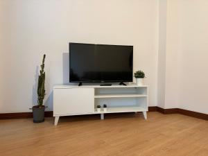 un centro de entretenimiento blanco con TV de pantalla plana. en Fantástico apartamento cerca de Santander en El Astillero