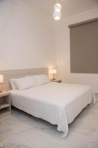 a white bedroom with a large white bed and a screen at CASA BIANCA Bella Vista in Panama City