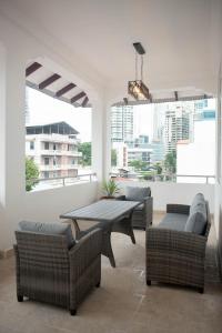 een woonkamer met een tafel, stoelen en ramen bij CASA BIANCA Bella Vista in Panama-Stad