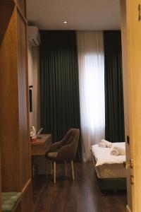 a bedroom with a bed and a desk and a window at Central Hotel Kutaisi in Kutaisi