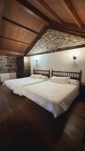 een groot wit bed in een kamer met een bakstenen muur bij Aldea Lamacido in Loiba