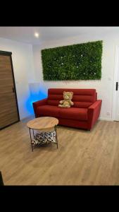 a teddy bear sitting on a red couch in a living room at Centre Quimper, animaux déclarés acceptés in Quimper