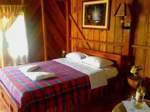 a bedroom with a bed with a plaid blanket at Suchipakari Amazon Eco -Lodge & Jungle Reserve in Puerto Misahuallí