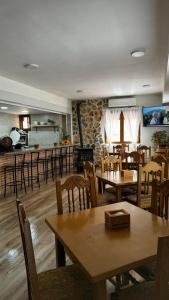 un restaurante con mesas y sillas de madera y una cocina en Casa rural Gerardo en Armallones