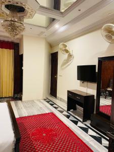 a living room with a television and a red rug at Executive Galaxy Guest House in Islamabad