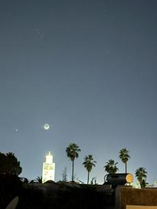 un edificio con palmeras y luna en el cielo en Riad Majdoulina chez JIJI en Marrakech