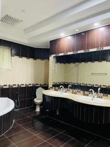 a bathroom with two sinks and a toilet and a mirror at Executive Galaxy Guest House in Islamabad