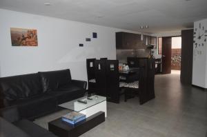 sala de estar con sofá negro y cocina en Departamento de lujo Condominio ADMIRA, en Cuenca