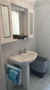 La salle de bains est pourvue d'un lavabo blanc et d'un miroir. dans l'établissement Balestrate holiday home 70 Mq, à Balestrate