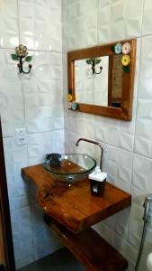 un bagno con lavandino in vetro su un bancone in legno di Recanto KAIRÓS a Visconde De Maua