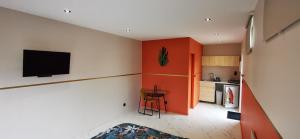 a kitchen with an orange wall with a television on it at Chez Aurel et Nico. in La Lande-de-Fronsac